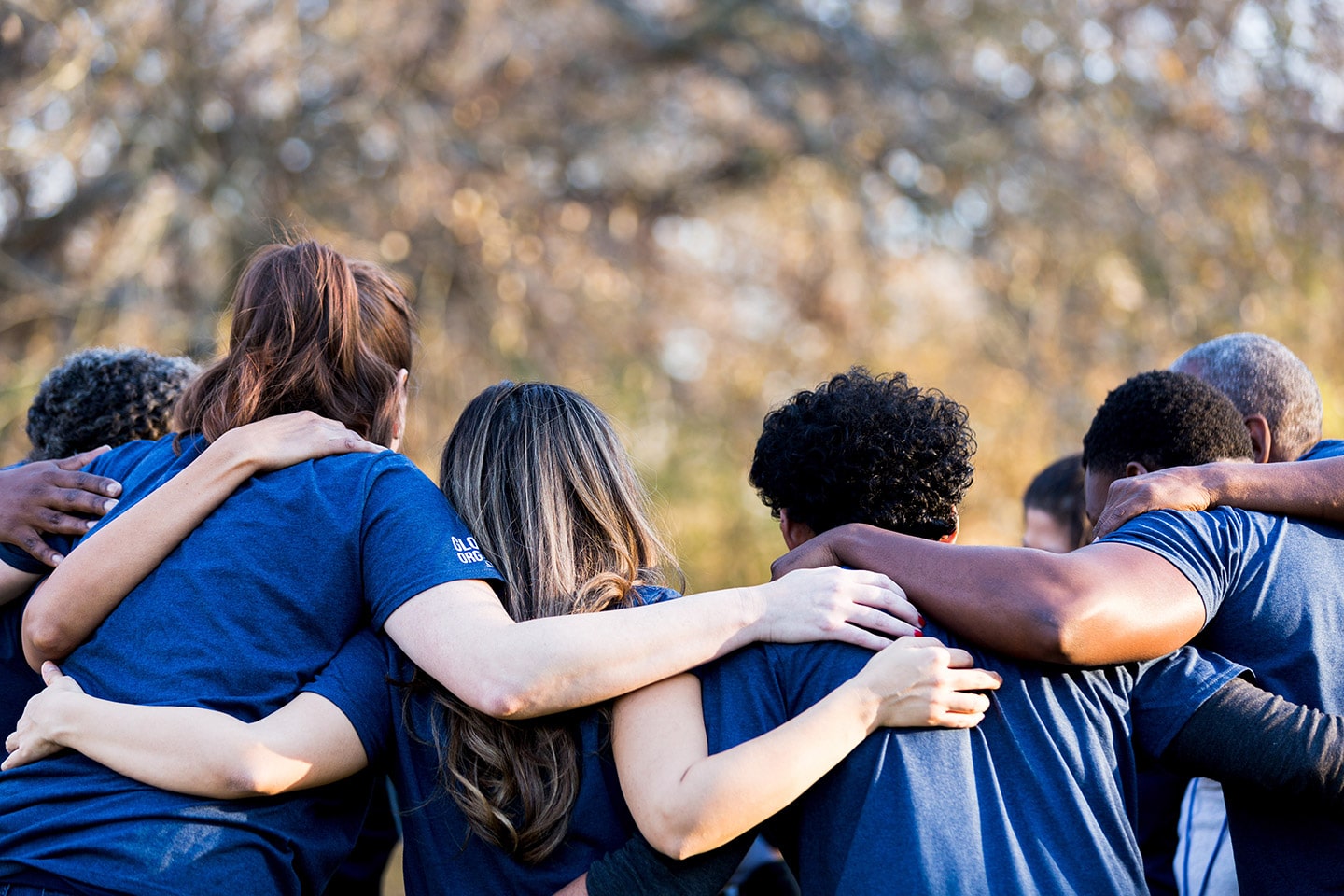 Volunteers standing in a line outdoors with their arms around one another