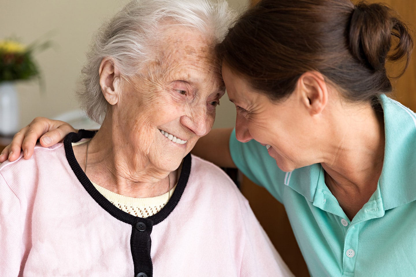 An older woman and a younger woman leaning their heads together, smiling