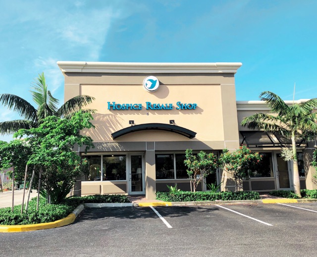 The Boca Raton resale shop, a tan building with Hospice Resale Shop lettering and a leaping-dolphin emblem above it, palms either side of the entrance