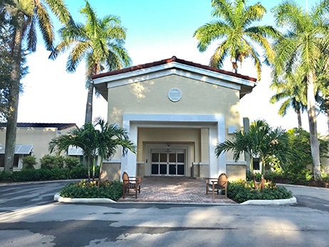 A covered entrance portico framed by palm trees at the Boca Raton building