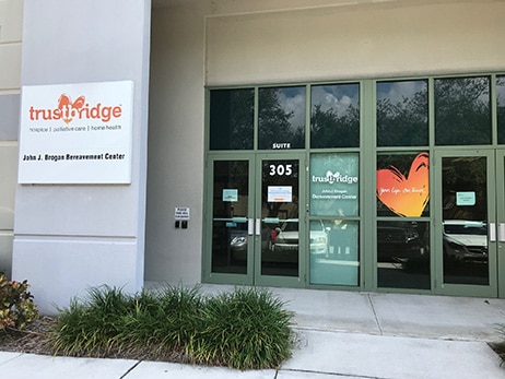 The glass doors of Suite 305, signposted John J. Brogan Bereavement Center