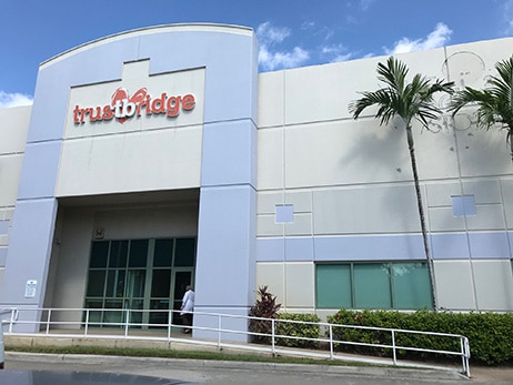 The Trustbridge Central Distribution Facility, a grey warehouse building with the Trustbridge sign above its entrance