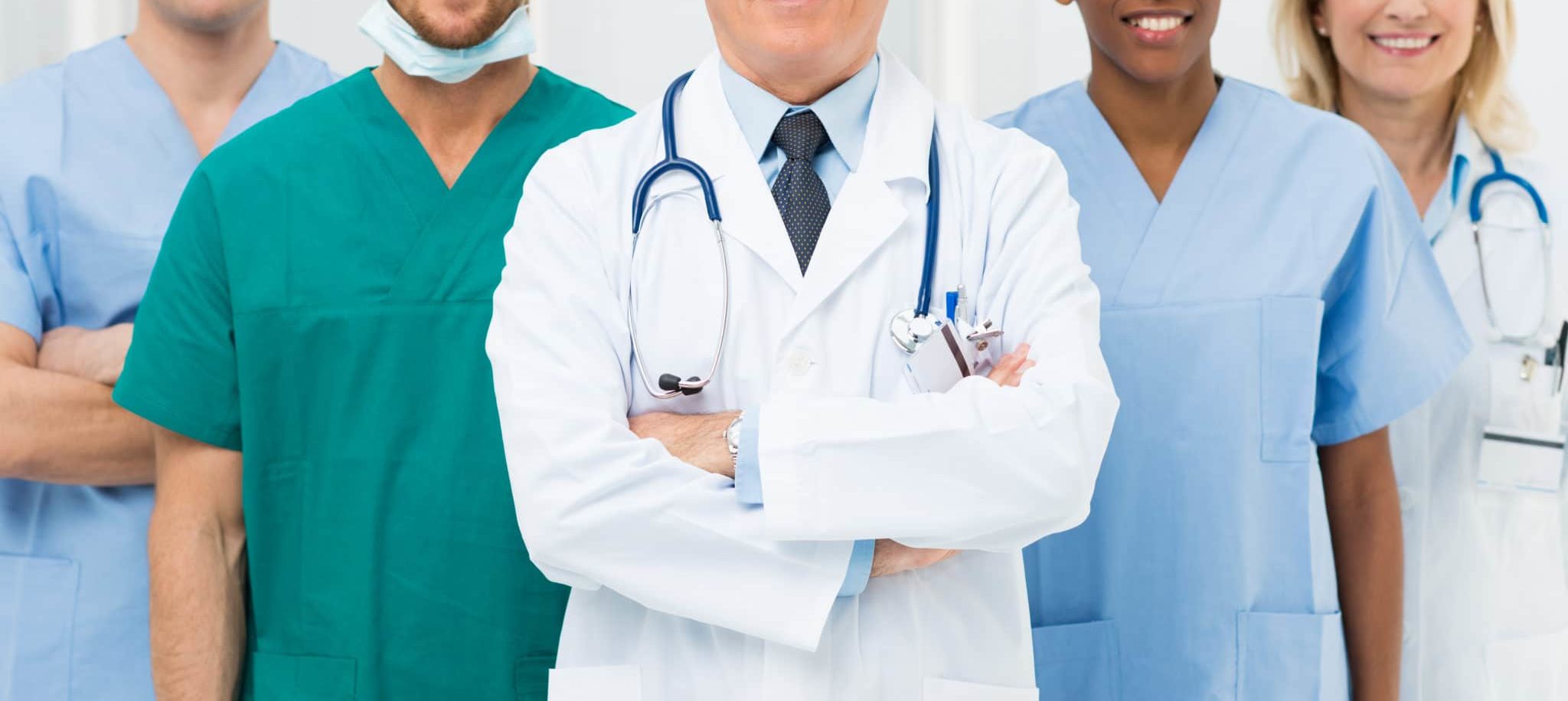 Five Trustbridge clinicians in scrubs and lab coats standing together