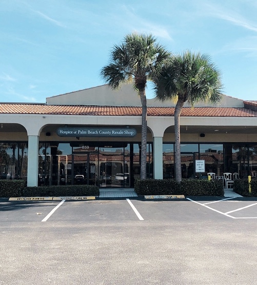 The Juno Beach resale shop seen from its car park, a low tiled arcade with palms in front of it