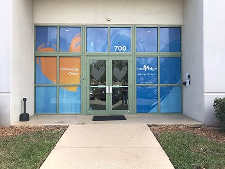The Knowledge Center entrance, its glass doors printed with the Trustbridge heart