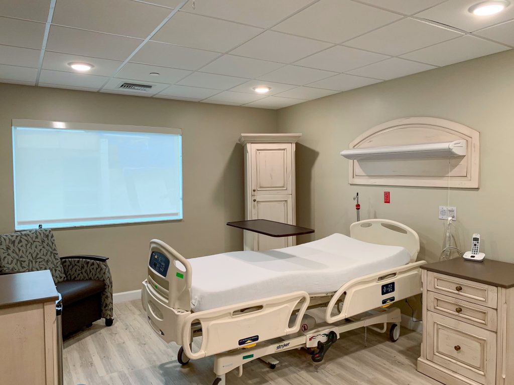 A patient room at the Care Center at John Knox Village, with a hospital bed, a recliner, a cordless telephone on the nightstand and a shaded window