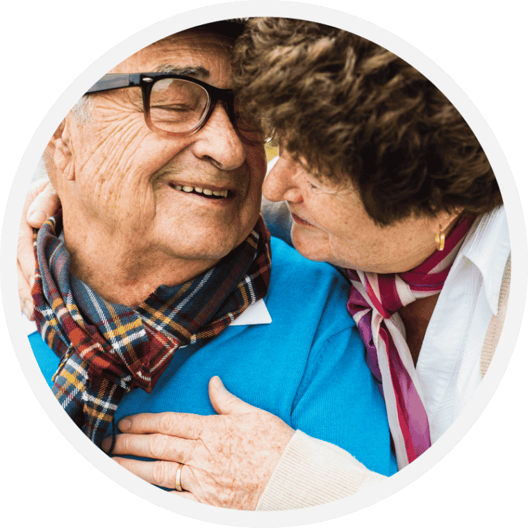 An older couple holding each other close, one resting a hand on the other's chest