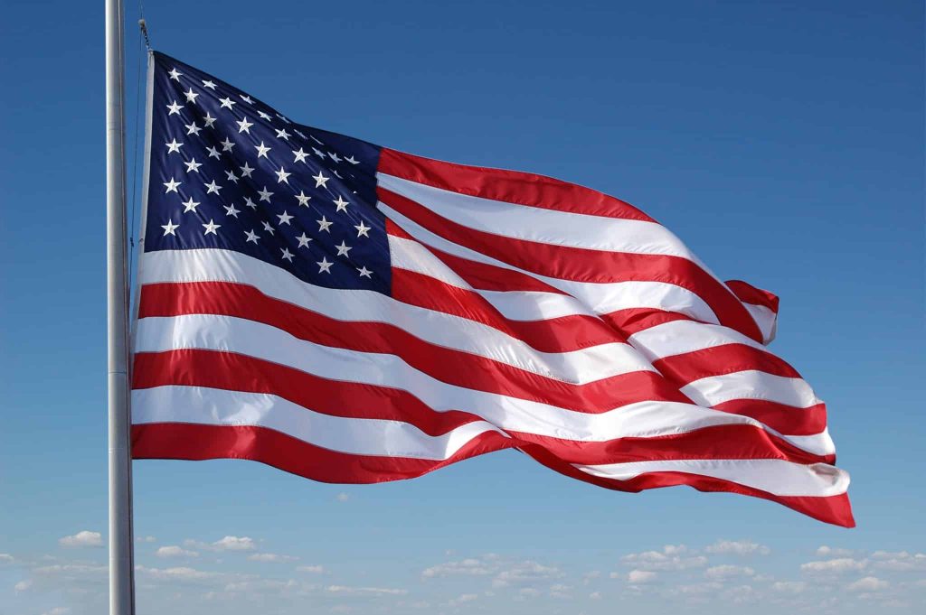The flag of the United States flying from a pole against a clear sky