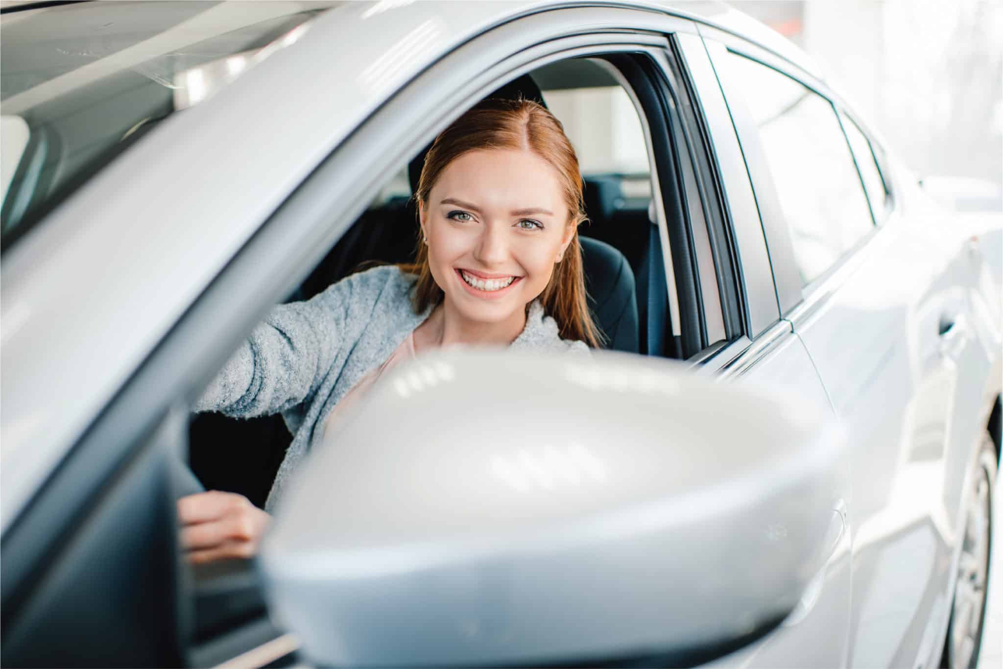 A driver smiling from the window of a car