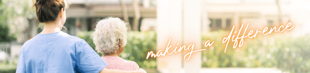 A Trustbridge caregiver in scrubs walking arm in arm with an older woman along a garden path, beside the handwritten words making a difference