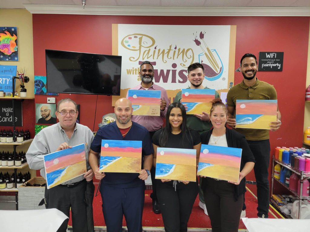 Seven fellows and staff holding up the beach scenes they painted at a Painting with a Twist team evening