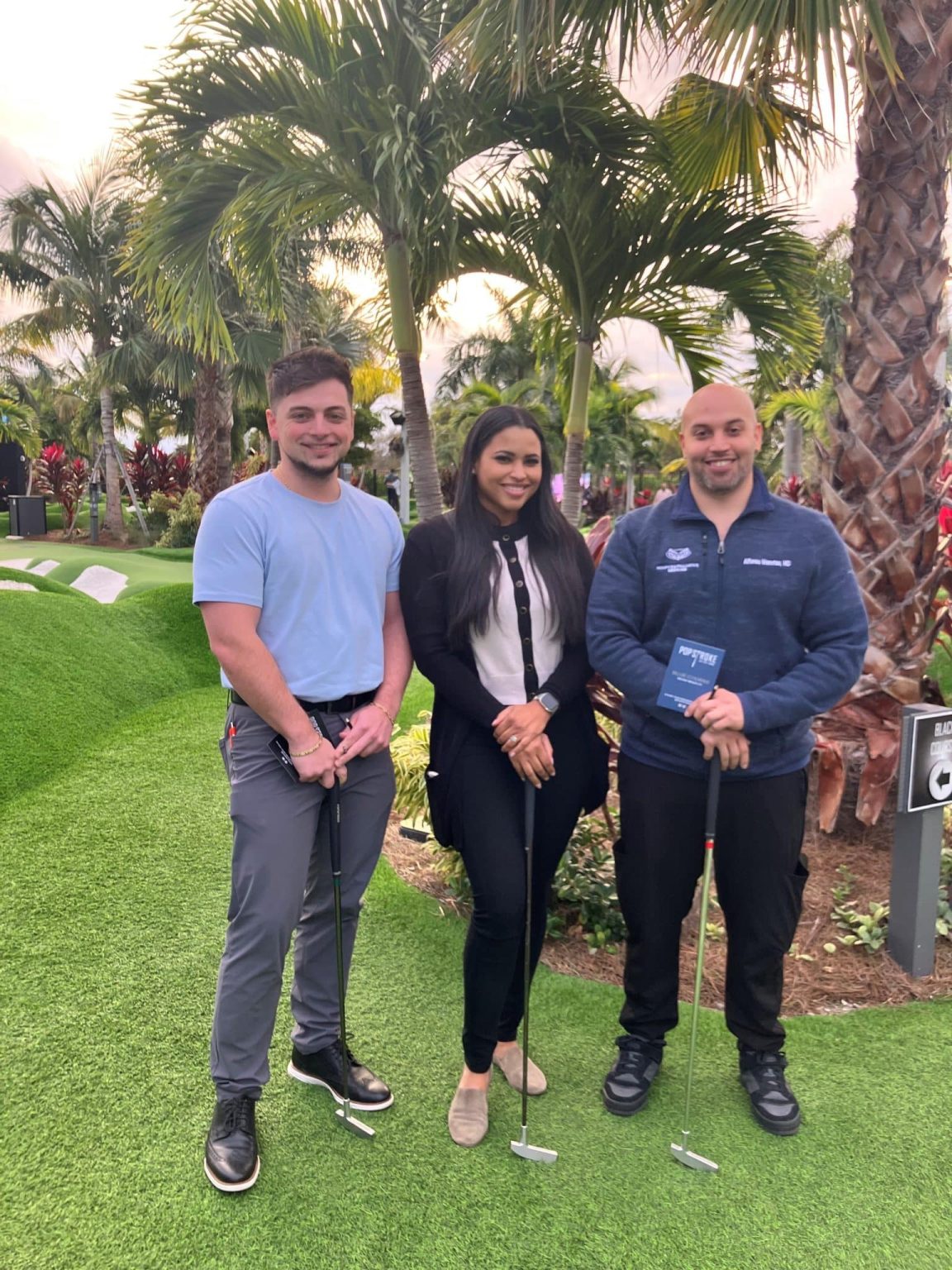 Three fellows standing together on the green at the wellness outing