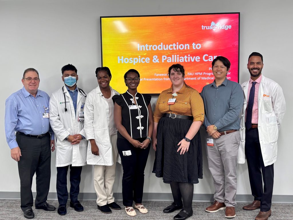 Eight physicians and staff standing in front of a screen reading Introduction to Hospice & Palliative Care at fellowship orientation